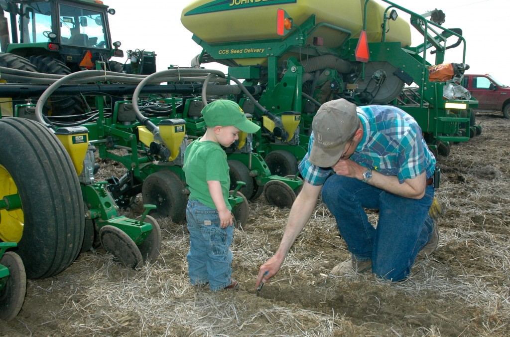 SDCUC president Brian Smith and his son examine the soil while utilizing no-till to plaint this year's corn crop.